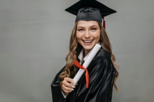 Joyful woman in graduation gown and cap, celebrating academic achievement.